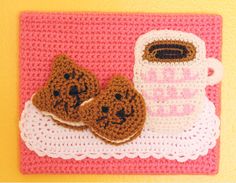 two crocheted cookies and a mug on a doily