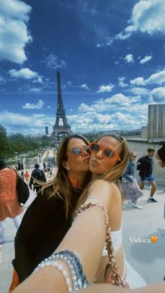 two women are kissing in front of the eiffel tower