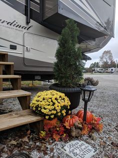 an rv parked next to some steps with flowers and pumpkins on the ground in front of it