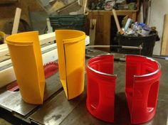 three plastic cups sitting on top of a metal table next to a machine in a shop