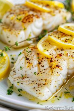 fish with lemons and herbs on a white plate