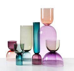 several different colored vases sitting on top of a white table next to each other