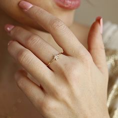 a close up of a person wearing a gold ring with a diamond on it's finger