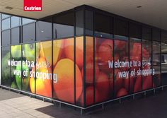 a large advertisement on the side of a building in front of a bus stop with fruit and vegetables