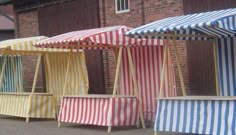 four striped umbrellas lined up in front of a brick building