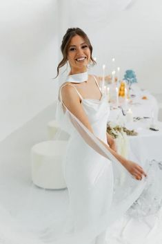 a woman in a white dress standing next to a table