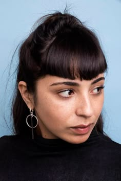 a close up of a person with a black shirt and some earrings on her head