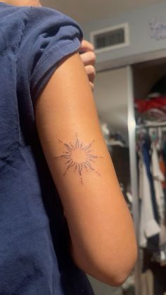 a woman's arm with a tattoo that has a sun design on the side