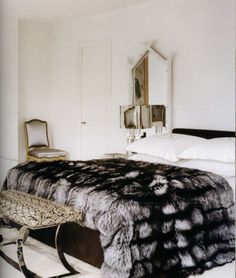 a bedroom with a bed, chair and mirror