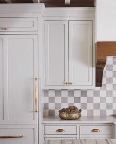 a kitchen with white cabinets and checkered backsplash