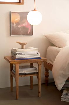 a small table with books on it next to a bed