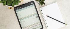 a cell phone sitting on top of a desk next to a notepad and pen