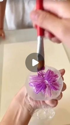 a person holding a brush in their hand with purple flowers on the inside of it