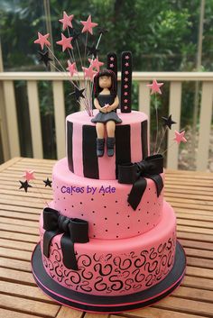 a pink and black cake sitting on top of a wooden table