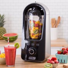 a blender filled with lots of fruit on top of a counter next to bowls of fruit