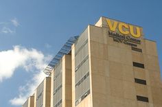 the vcu medical center building is shown against a blue sky with clouds in the background