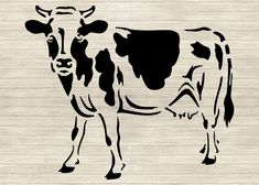 a black and white cow standing on top of a wooden floor next to a wall