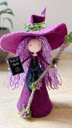 a small purple witch doll holding a broom