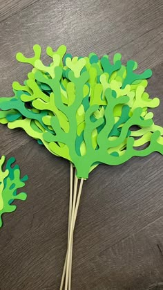 a green tree made out of paper sitting on top of a wooden table next to scissors