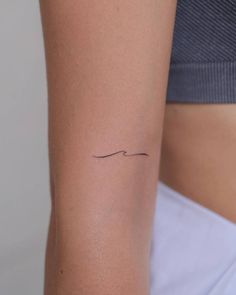 a woman's arm with a small wave tattoo on the left side of her right arm