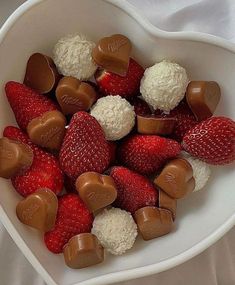 a heart shaped bowl filled with chocolate covered strawberries and marshmallow candies