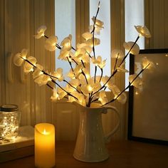 a vase filled with white flowers next to a lit candle