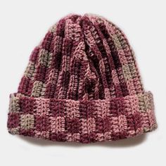 a pink and grey knitted hat on a white surface