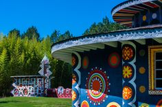 a colorfully painted building in the middle of a field with trees and bushes behind it