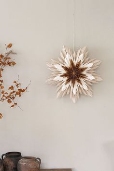 a white wall with two vases and a star shaped object hanging on the wall