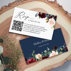 two business cards sitting on top of a piece of wood next to flowers and greenery