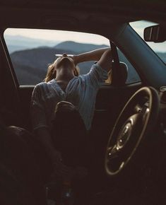 a woman sitting in the driver's seat of a car with her head up