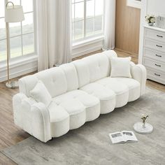 a white couch sitting on top of a rug in a living room next to a window