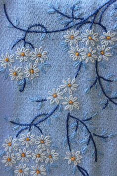 some white flowers on a blue towel with black stems and small yellow dots in the middle