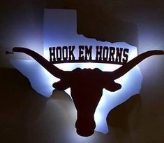 the texas longhorns logo is lit up against a dark wall with blue lights