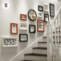 there are many framed pictures on the wall next to the stair case and handrail