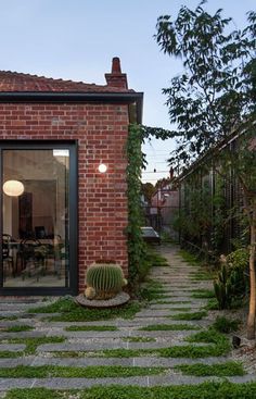 a brick building with grass growing on the ground next to it and an open patio area