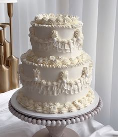 a three tiered white wedding cake sitting on top of a table next to a lamp