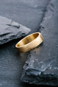 a gold wedding ring sitting on top of a rock