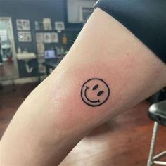 a small smiley face tattoo on the right leg, with a black circle around it