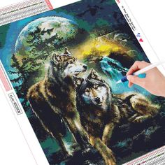 a person is holding a marker and drawing on a piece of fabric with wolfs in the background