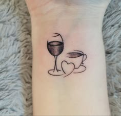 a woman's foot with a wine glass and heart tattoo on it