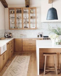 a kitchen with wooden cabinets and white counter tops next to a rug on the floor