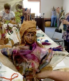 the woman is wearing a headdress and holding something in her hand while others work on crafts