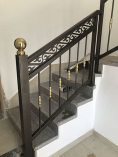 an iron stair railing with brass finial and handrails in a home setting