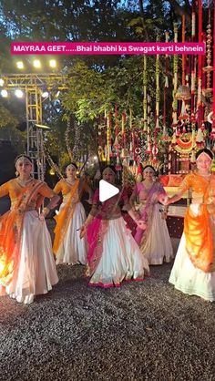 several women in colorful dresses are dancing on the ground with lights and decorations behind them