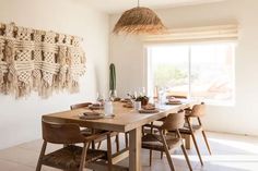 a dining room table and chairs in front of a wall hanging with woven baskets on it