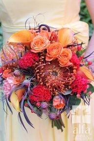 the bride's bouquet was made up of orange and red flowers, feathers, and foliage