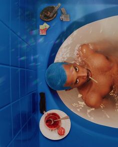 a man with blue hair is in the bathtub next to a plate and toothbrush