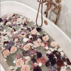 a bathtub filled with lots of flowers next to a faucet