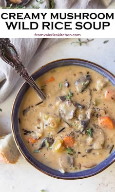 creamy mushroom wild rice soup in a blue bowl with a spoon and bread on the side